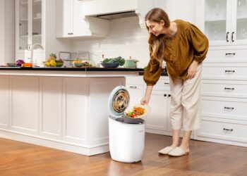 A woman placing food scraps into a countertop bin as part of her daily composting routine in a New York City kitchen.