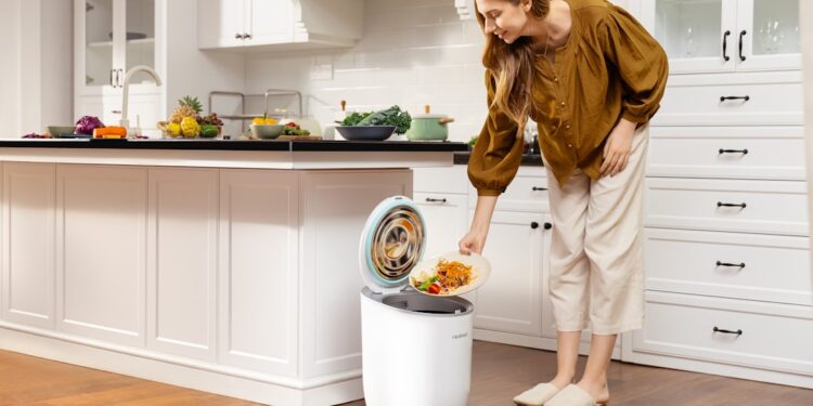 woman-kitchen-compost-bin-unsplash - NYCwebzine A woman placing food scraps into a countertop bin as part of her daily composting routine in a New York City kitchen.