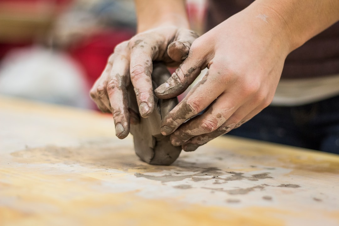 A sculptor shaping clay in a workshop, the kind of hands-on studio environment offered by artist residencies.