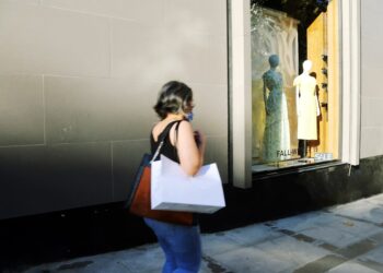 A focused woman carefully examining a designer jacket at New York City sample sales, building an intentional wardrobe.