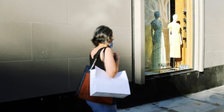 woman-shopping-clothing-unsplash - NYCwebzine A focused woman carefully examining a designer jacket at New York City sample sales, building an intentional wardrobe.