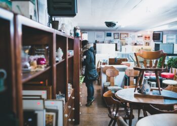 A woman carefully inspects a vintage furniture piece in a Manhattan dealer showroom, evaluating provenance and condition