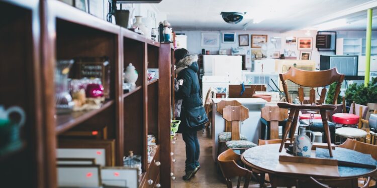antique-furniture-person-unsplash - NYCwebzine A woman carefully inspects a vintage furniture piece in a Manhattan dealer showroom, evaluating provenance and condition