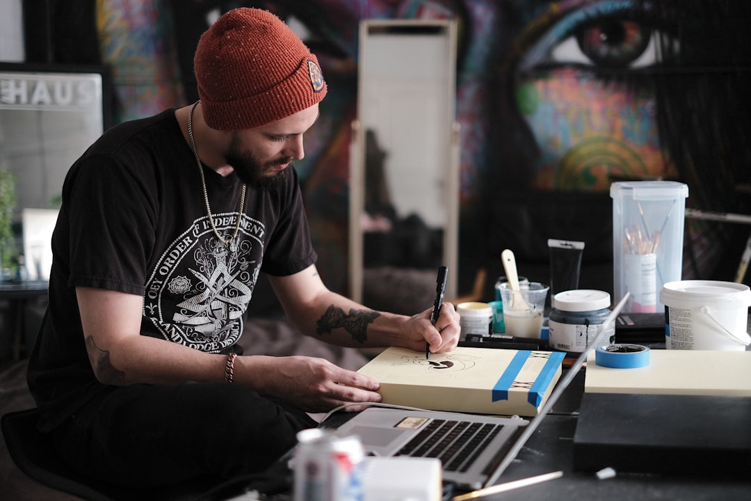 An emerging artist researches affordable artist space programs on a laptop inside a shared NYC studio workspace