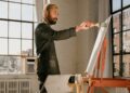 artist-painting-studio-brooklyn-unsplash - NYCwebzine An emerging artist works inside an affordable artist space in Brooklyn, surrounded by canvases and natural light