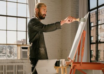 An emerging artist works inside an affordable artist space in Brooklyn, surrounded by canvases and natural light