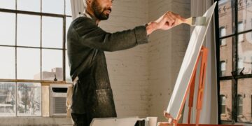 artist-painting-studio-brooklyn-unsplash - NYCwebzine An emerging artist works inside an affordable artist space in Brooklyn, surrounded by canvases and natural light