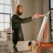 An emerging artist works inside an affordable artist space in Brooklyn, surrounded by canvases and natural light