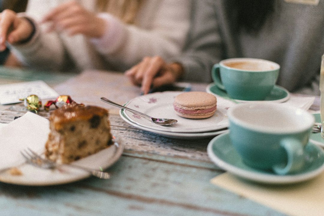 2 friends enjoying pastries together at a table inside one of NYC's best gluten-free bakeries, sharing a relaxed cafe moment.