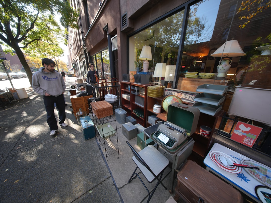 A man browses a curated selection of vintage furniture in a New York City dealer space, comparing mid-century modern pieces.