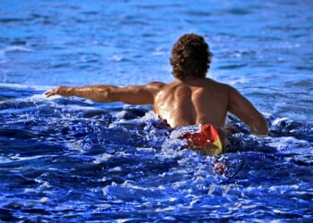 A swimmer wading into the open water at Brighton Beach, representing the open-water culture of a New York City swimming club