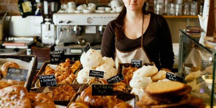 woman-choosing-pastry-bakery-counter-unsplash - NYCwebzine A woman carefully selecting a pastry at a gluten-free bakeries counter in New York City, surrounded by baked goods.