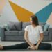 woman-stretching-home-unsplash - NYCwebzine A woman practicing a recovery routine on a yoga mat in a compact New York City apartment, surrounded by soft morning light