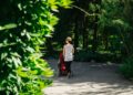 woman-walking-botanical-garden-path-unsplash - NYCwebzine A woman walks along a tree-lined path at one of New York City's botanical gardens in autumn