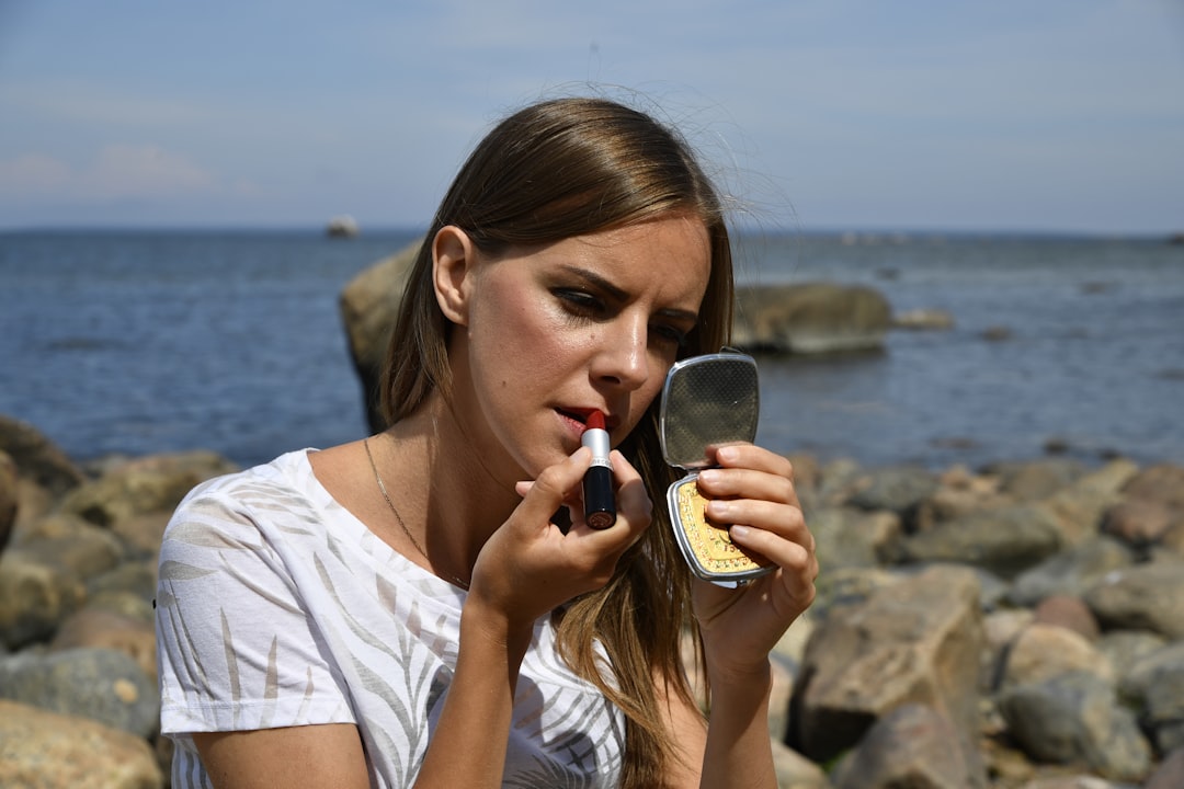 A woman applying primer to her face in preparation for a summer makeup routine in New York City