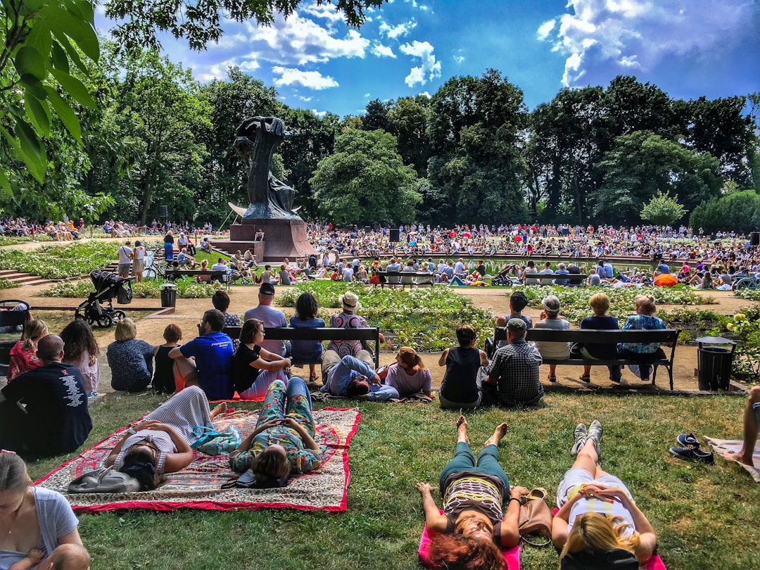 A diverse crowd of people enjoying free outdoor concerts in a New York City park on a summer evening