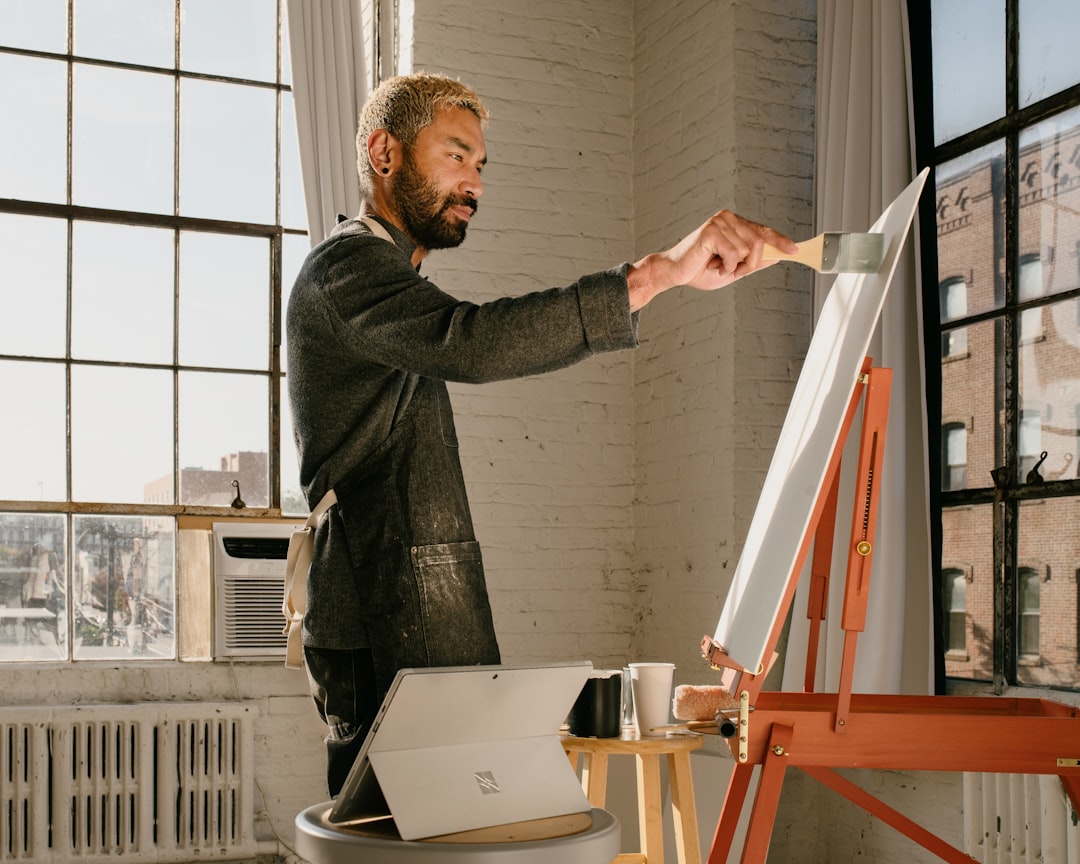 An emerging artist works inside an affordable artist space in Brooklyn, surrounded by canvases and natural light