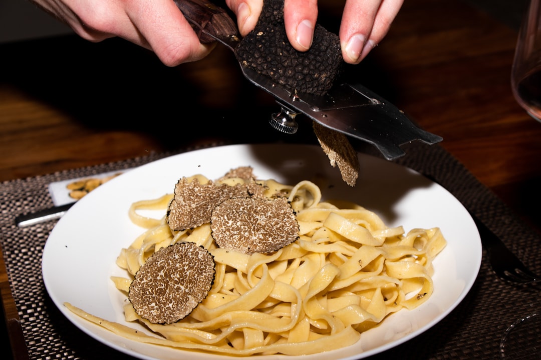A chef shaves fresh Alba white truffle over handmade pasta at one of New York City's most celebrated truffle dinners