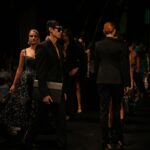 An emerging designer adjusts a garment backstage before a New York Fashion Week runway show