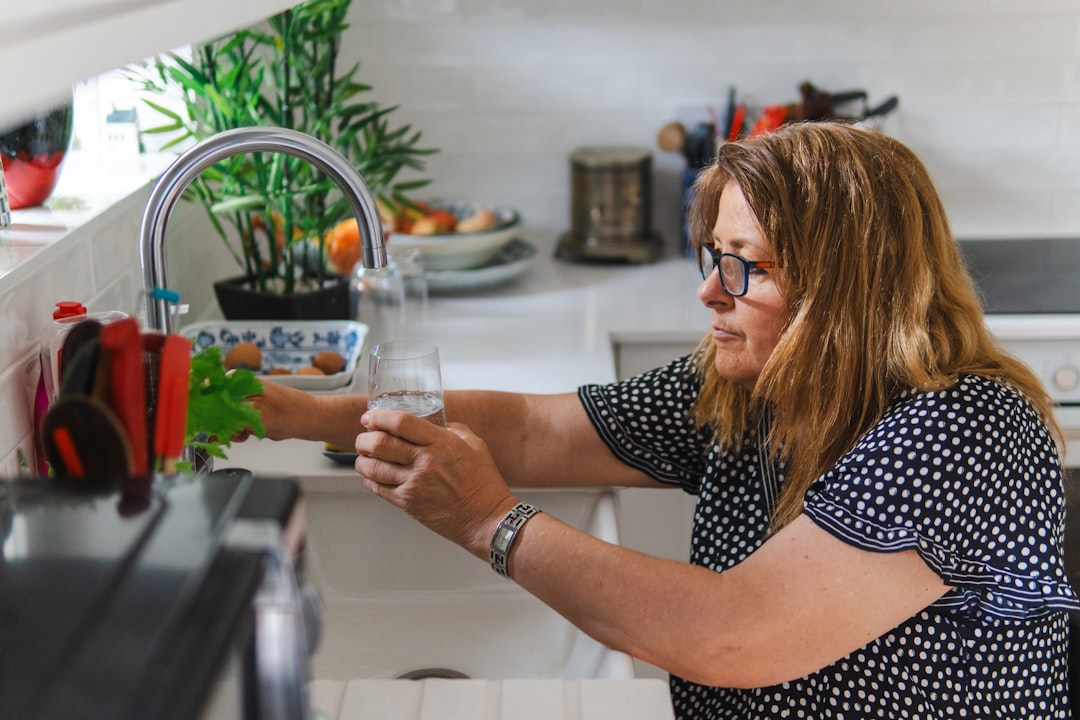 A woman arranging labeled glass jars on an open shelf as part of building a lower-waste kitchen in a New York City apartment