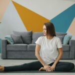 A woman practicing a recovery routine on a yoga mat in a compact New York City apartment, surrounded by soft morning light